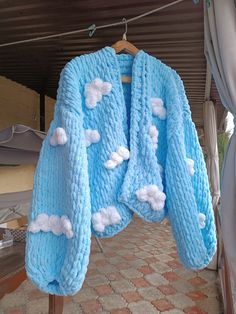 a blue sweater with clouds on it hanging from a clothes line in front of a building