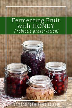 four jars filled with fruit sitting on top of a table