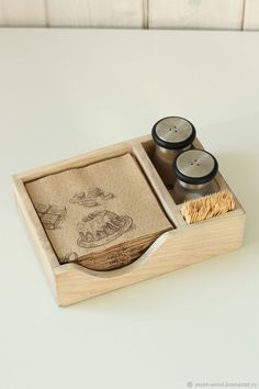 two candles are sitting in a wooden box on a white table top with a towel