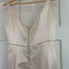 a white dress hanging on a wooden hanger