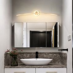 a bathroom with a sink, mirror and lights on the wall above it's counter