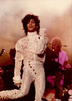 a man in white outfit standing on stage