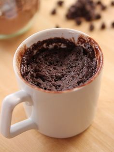 a white cup filled with chocolate cake sitting on top of a wooden table