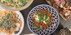 four plates with different types of food sitting on top of a table next to each other