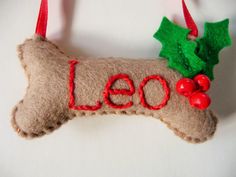 a dog bone ornament hanging on a wall with the word leo written in red