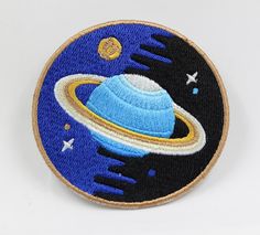 an embroidered patch with the image of saturn on it