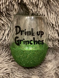 a wine glass with the words drink up grinies on it sitting on a furry surface