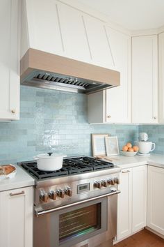 a stove top oven sitting inside of a kitchen next to white cabinets and counter tops