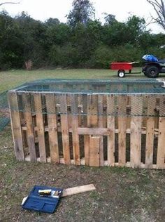 a fence made out of wooden pallets with a tractor and trailer in the background