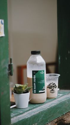 a bottle of milk sitting on top of a table next to a potted plant