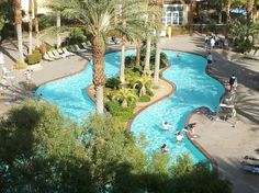 an aerial view of a pool surrounded by palm trees and people swimming in the water