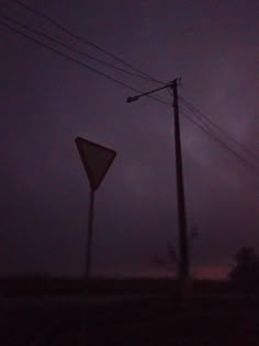 a street sign sitting on the side of a road next to power lines and telephone poles