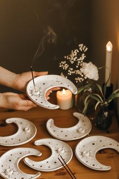 a person holding a lit candle near some decorative plates