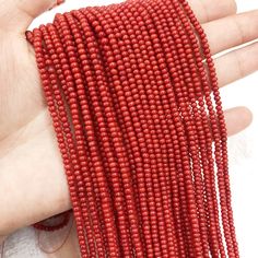 red seed beads are being held by someone's hand