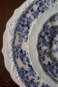 three blue and white plates sitting on top of a wooden table