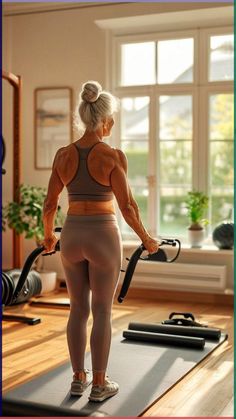 a woman is standing on a yoga mat with her back to the camera and holding a resistance band