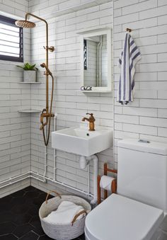 a white bathroom with black tile flooring and wall to wall tiles on the walls