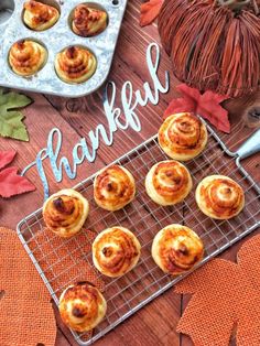 pumpkin cinnamon rolls on a cooling rack with the words happy thanksgiving in front of them