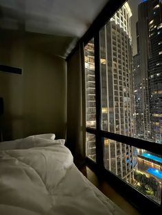 a bedroom with a view of the city from it's window sill at night