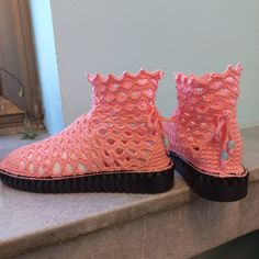 a pair of pink crocheted shoes sitting on top of a stone countertop