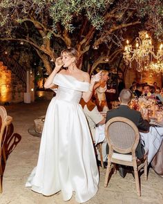 a woman in a white dress standing next to a table