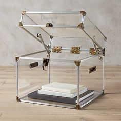 a clear glass case with metal handles and latches on the bottom is holding books