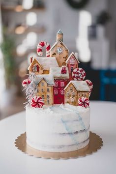 a white cake topped with candy houses and candies