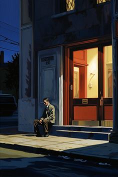 a man sitting on the sidewalk in front of a building at night with his head down