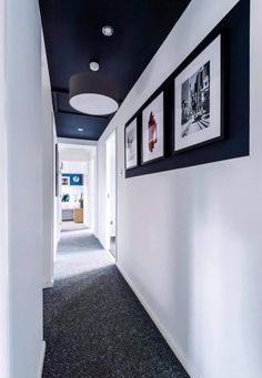 an empty hallway with pictures hanging on the wall and carpeted flooring in front of it