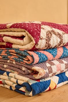 a stack of quilts sitting on top of a wooden table