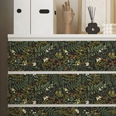 the drawers are decorated with green and white floral wallpaper, along with decorative objects