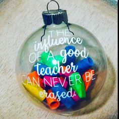 a glass ornament filled with colorful crayons on top of a table