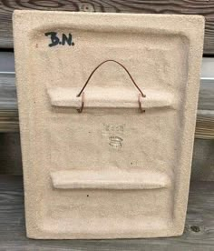 a cement box with some writing on it and a brown string hanging from the top