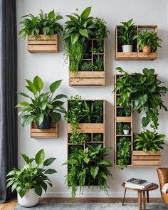 several wooden boxes filled with green plants on a wall next to a chair and table