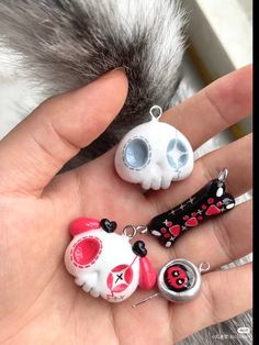 someone is holding three different key chains in their hand, one with a skull and the other with a cat's eye