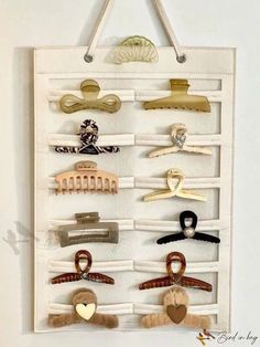 a white wall hanging with lots of hair clips on it's sides and hooks