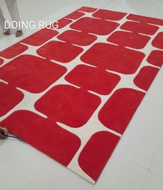 a red and white rug on the floor in a room with people standing around it