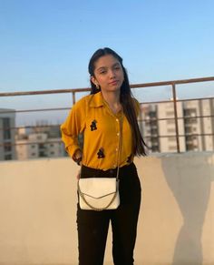 a woman standing on top of a roof next to a white purse and wearing black pants