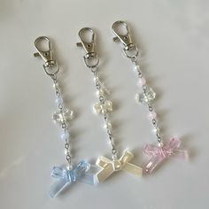 three key chains with bows and pearls on them, one has a chain attached to it