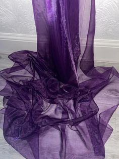 purple sheer fabric on the floor in front of a white wall