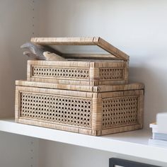 two wicker boxes sitting on top of a white shelf