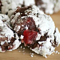 chocolate crinkle cookies covered in powdered sugar and cherries on a wooden table