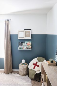 a living room with blue walls and a cross pillow on the chair next to it