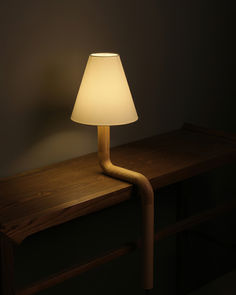 a lamp that is sitting on top of a wooden table next to a dark wall