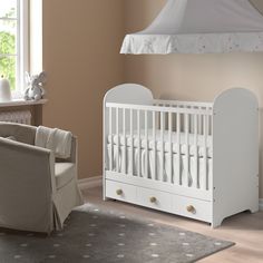 a baby's room with a white crib, chair and bed in it