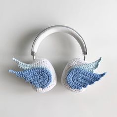 two crocheted angel wings are hanging from a hook on a white wall, one is blue and the other is white