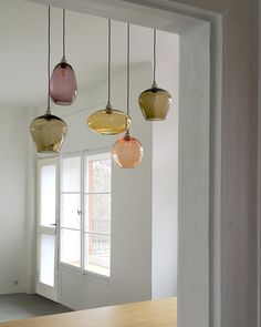 three different colored lights hanging from the ceiling in a room with white walls and wood flooring