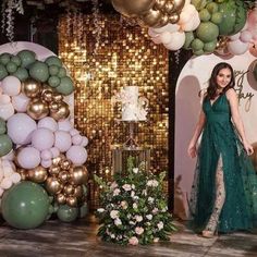 a woman in a green dress standing next to some balloons and cake on a table