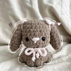 a crocheted stuffed animal sitting on top of a white bed sheet with hearts