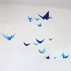 several blue origami birds are flying in the sky